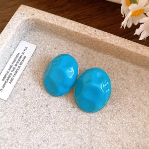 Close-up detail of turquoise crumpled oval stud earrings with an enamel finish