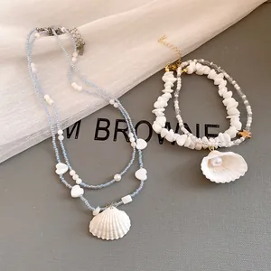 Macro view of summer island style beaded necklaces with white shell and heart pendants.