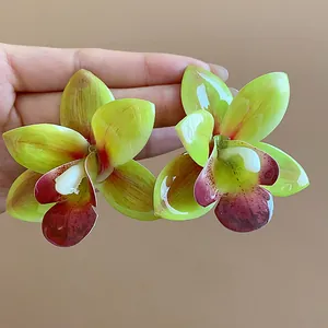 Detailansicht der lebhaften grünen und weinroten Orchideenblüten-Ohrringe aus Harz.