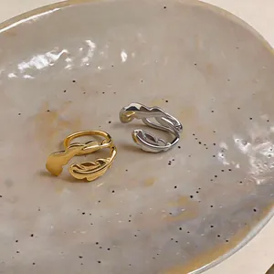 Détail de bagues d'oreilles en forme de plume plaquées or 18 carats, or et argent