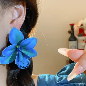 Detailansicht eines blauen Orchideen-Ohrrings am Ohr mit eleganten Details aus Harz