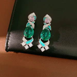 Macro view of palace style drip oil earrings featuring emerald green zirconia drops and pink gems
