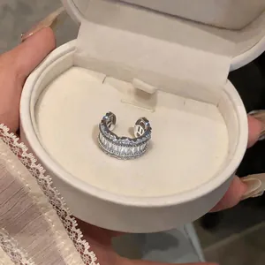 Macro view of a sparkling cubic zirconia C-shaped ear cuff inside a white jewelry gift box