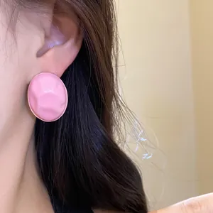 Detailed close-up showing a stylish pink crumpled oval stud earring on a model's ear
