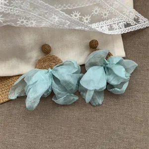 Vista dettagliata di orecchini a fiore in chiffon azzurro con base in paglia intrecciata