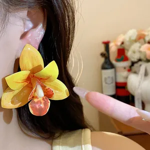 Nahaufnahme von eleganten gelben Orchideen-Ohrringen mit Silbernadeln am Ohr des Modells