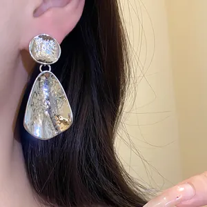 Primo piano dettagliato della trama degli orecchini a goccia in argento su una modella