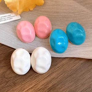 Macro detail of wrinkled drip oil oval stud earrings in pink, blue, and white colors