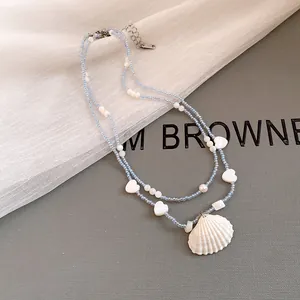 Detailed view of beach-themed double-layer necklace with blue beads and seashell pendant