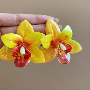 Makro-Detail von eleganten gelben Orchideen-Ohrsteckern mit glänzendem Harz-Finish