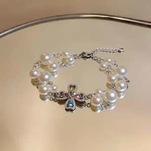 Close-up of double-layered pearl bracelet with colorful heart zircon cross pendant.