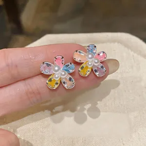 Close-up of sweet flower stud earrings featuring colorful zircons and small pearls.