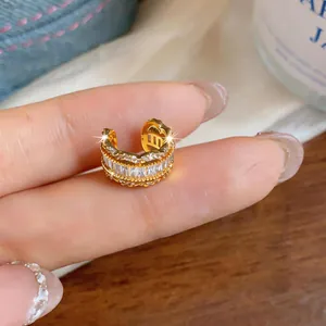 Detail view of a gold-toned C-shaped ear cuff with sparkling zircon inlay