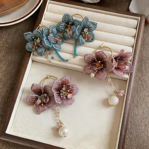 Detailed view of handmade knitted flower earrings with glass bead tassels and pearls.
