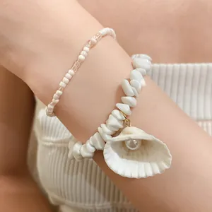 Detailed close-up of summer shell bead bracelets with a pearl shell charm on a wrist.