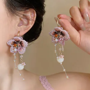 Close-up of pink knitted flower earrings with elegant glass bead tassels shown on a model.