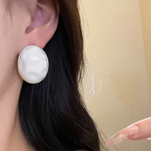 Detail showing the wrinkled white oil-dripped texture of the oval stud earrings