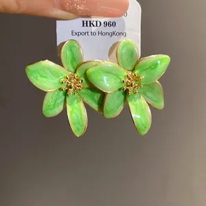 Vue macro détaillée de boucles d'oreilles fleurs en émail vert et étamine dorée