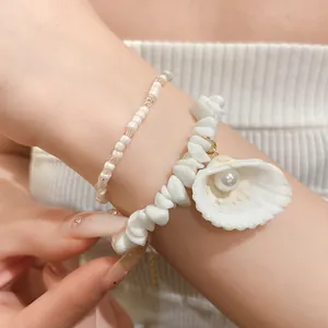 Detailed macro shot of layered white beaded bracelets with shell and pearl pendant charm