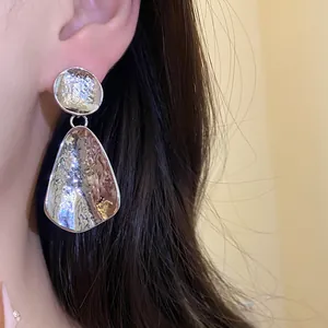 Dettaglio di orecchini a pendente in argento martellato dal design a goccia moderno