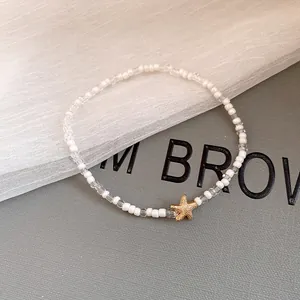 Close-up of beach-style necklace with white beads and golden starfish charm
