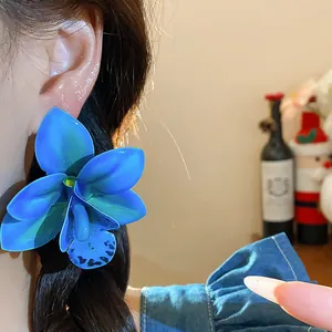 Detailansicht von blauen Orchideen-Ohrsteckern aus Stoff- und Harzmaterialien
