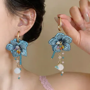 Detailed close-up of blue embroidered flower earrings with colorful glass bead tassels