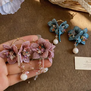 Detail of handmade knitted flower earrings with colorful glass beads and pearl tassels