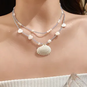 Detailed view of a double-layered blue beaded necklace with white shell pendant
