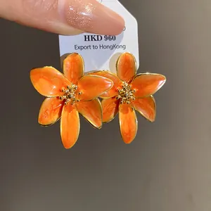 Gros plan détaillé de boucles d'oreilles fleurs orange vintage avec bord doré