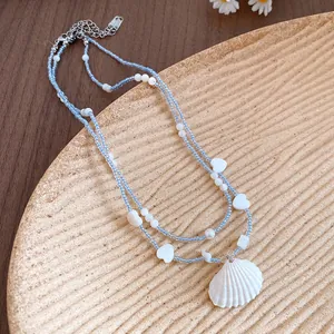 Detailed macro view of summer style blue beaded necklace with a white shell pendant detail