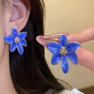 Gros plan d'élégantes boucles d'oreilles fleurs en émail bleu au design de style vintage