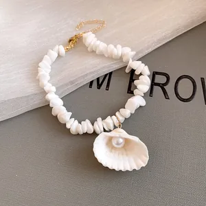 Detail of a summer island style white shell beaded necklace with a pearl pendant.