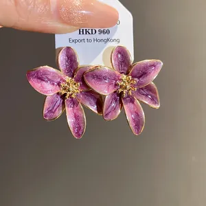 Vue détaillée des boucles d'oreilles fleur en émail violet avec centre doré chic