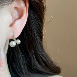 Detailed view of elegant French vintage hoop earrings with double white pearls worn on ear