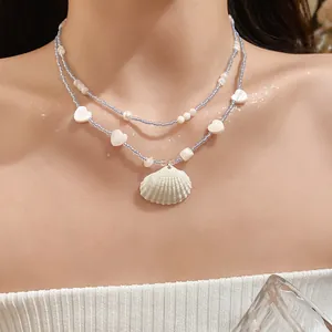 Close-up of summer island style blue beaded layered necklace with shell pendant