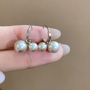 Macro view of French retro hoop earrings featuring dual pearls on a gold finish