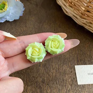 Macro view of light green resin rose flower stud earrings with silver needle detail