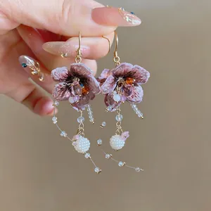 Detailed view of handmade knit flower earrings with elegant long glass bead tassels
