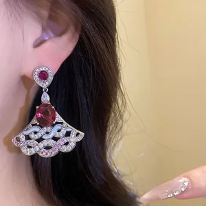 Close-up of elegant fan-shaped drop earring with sparkling red and pink zircons