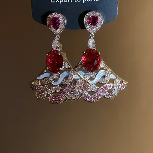Detailed macro view of zirconia oval dangle earrings with red stones and enamel