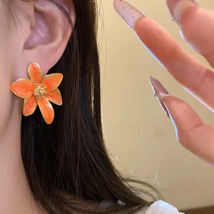 Gros plan détaillé des boucles d'oreilles fleurs orange sur une oreille modèle