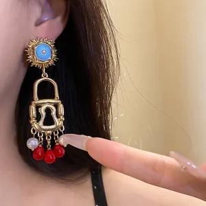 Vintage bohemian gold sun lock earrings with blue enamel center and red bead dangles