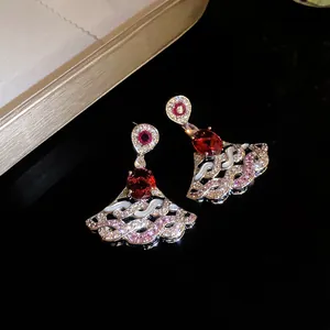 Detailed macro shot of luxury fan-shaped drop earrings featuring red zircon and intricate wave patterns
