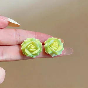 Detailed close-up showing light green resin rose flower stud earrings with silver needles
