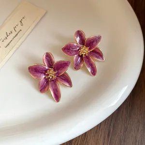 Détail de boucles d'oreilles fleurs en émail violet vintage avec bords dorés élégants
