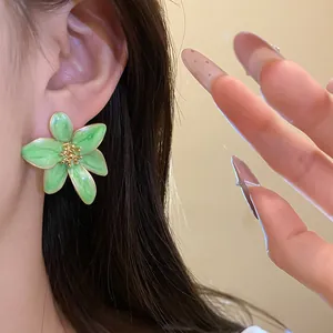 Gros plan d'une élégante boucle d'oreille fleur en émail vert avec centre doré rétro