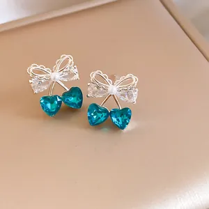 Primo piano di orecchini a ciliegia con cristalli blu a cuore e fiocco in argento