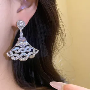 Elegant fan-shaped zirconia drop earrings worn on ear, showing luxury texture and details.