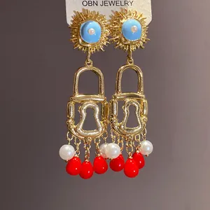 Detailed view of vintage enamel sun and padlock drop earrings with red beads